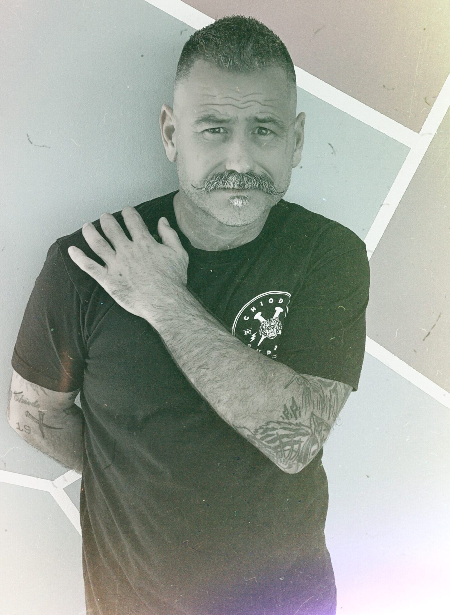 Artist ChiodoSupply standing against a wall with hand on shoulder.